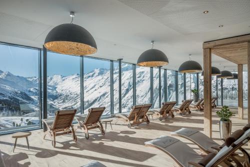 a room with chairs and a view of a mountain at SKI - GOLF - WELLNESS Hotel Riml in Hochgurgl