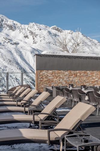 a row of lounge chairs in front of a mountain at SKI - GOLF - WELLNESS Hotel Riml in Hochgurgl