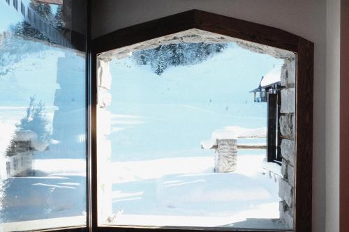 a window with a view of a snow covered yard at Hôtel La Grande Lanière in Les Gets
