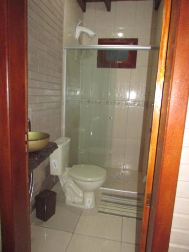 a bathroom with a toilet and a glass shower at Pousada Punta Cana in Estância Teixeira