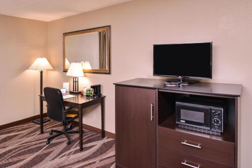 a hotel room with a desk and a television at Baymont by Wyndham Sioux Falls North,I-29,Russell St, Airport in Sioux Falls