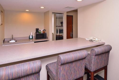 a kitchen with a large counter with two chairs at Baymont by Wyndham Sioux Falls North,I-29,Russell St, Airport in Sioux Falls