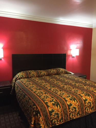 a bedroom with a bed with red walls and two lamps at Friendship Motor Inn in Los Angeles