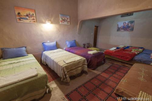 a room with three beds in a room at Kasbah Ounila in Aït Ben Haddou