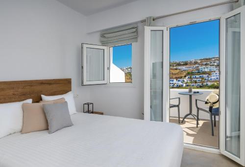 a bedroom with a bed and a balcony with a table at Cape Mykonos in Mýkonos City