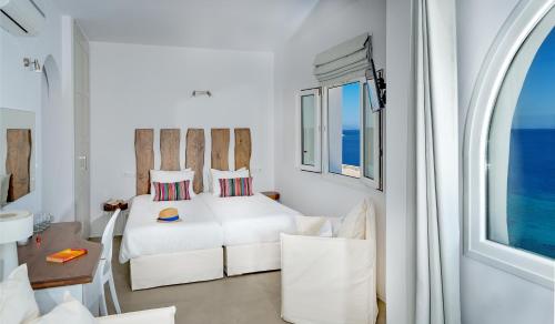 a white bedroom with a bed and a window at Cape Mykonos in Mýkonos City