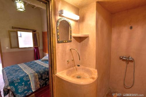 a bathroom with a sink next to a bed at Kasbah Ounila in Aït Benhaddou