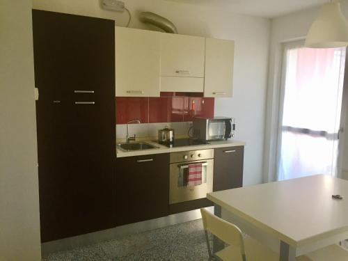a kitchen with red and white cabinets and a table at Casa Lampone in Trento