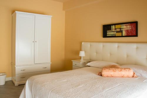a bedroom with a white bed and a white cabinet at Residenza Cavour in Acireale
