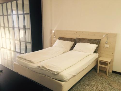 a bed with white sheets and pillows in a room at Casa Lampone in Trento