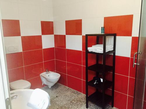 a red and white bathroom with a toilet and a sink at Casa Lampone in Trento