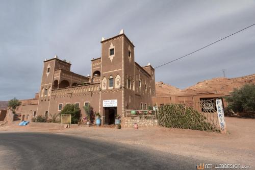 a large brick building in the middle of a road at Kasbah Ounila in Aït Ben Haddou