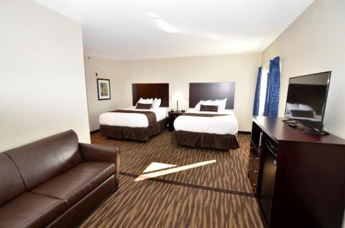 Habitación de hotel con 2 camas y sofá en Cornerstone Inn & Suites Oelwein en Oelwein