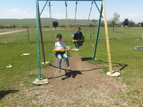 two children sitting on swings in a park at My home udabno in Udabno