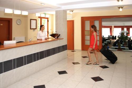 a woman with luggage walking in a hotel lobby at Hotel Korona in Harkány