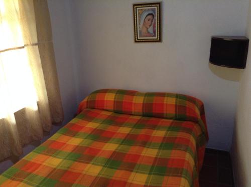 a bed in a room with a plaid blanket at Villa Liliana Lodge Mesa de los Santos in Los Santos