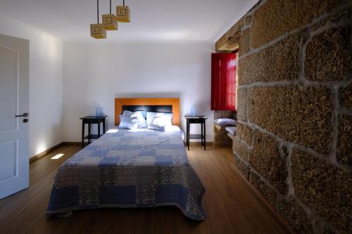 ein Schlafzimmer mit einem Bett und einer Ziegelwand in der Unterkunft Casas do Casinhoto - Casa Vista Aregos in Baião