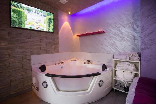 La salle de bains est pourvue d'une grande baignoire blanche et d'un éclairage violet. dans l'établissement Apartments Blue House, à Zlatibor