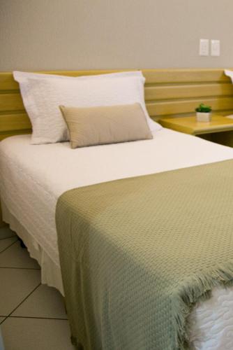 a bedroom with a large bed with white sheets and pillows at Hotel Sansaed in Cuiabá