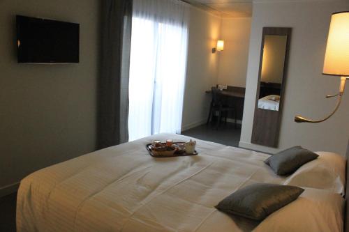 a bedroom with a bed with a bowl of food on it at The Originals Boutique, Hôtel La Chaussairie, Rennes Sud in Chartres-de-Bretagne