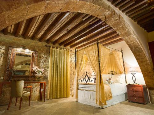 a bedroom with a canopy bed in a room with a stone wall at Oinoessa Traditional Boutique Guest Houses in Lofou