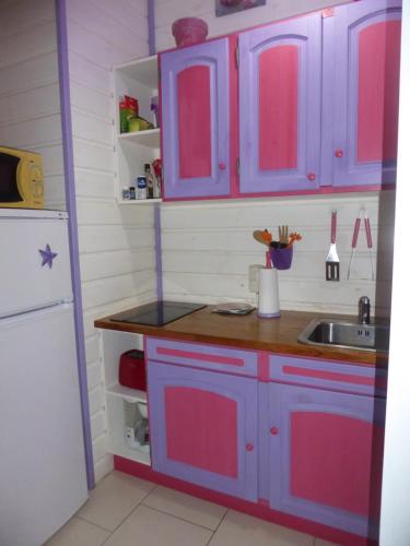 a kitchen with blue and pink cabinets and a sink at Coco Bungalows in Sainte-Rose