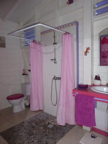 a bathroom with a pink shower curtain and a toilet at Coco Bungalows in Sainte-Rose