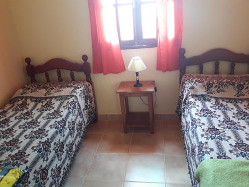 a bedroom with two beds and a table with a lamp at Cabaña Los Molles in Cachí