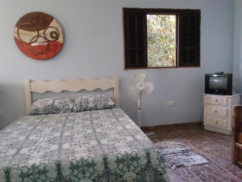 a bedroom with a bed and a tv and a window at Ilha Céu Sol in Ilhabela