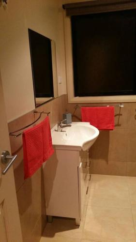 a bathroom with a white sink and red towels at Pebbles Beach Retreat in Cowes