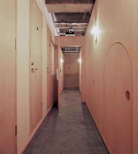 an empty hallway with orange walls and a long corridor at Iwashi Building Hostel in Akune
