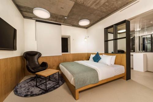 a bedroom with a bed and a black chair at Delight Hotel Jamsil in Seoul