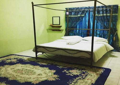 - une chambre avec un lit à baldaquin et un tapis bleu dans l'établissement Homestay Pagar Buruk Ipoh, à Ipoh