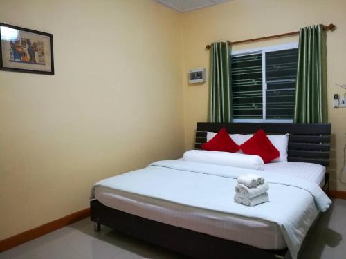 a bedroom with a bed with red pillows and a window at Lampang Lanna Home in Lampang