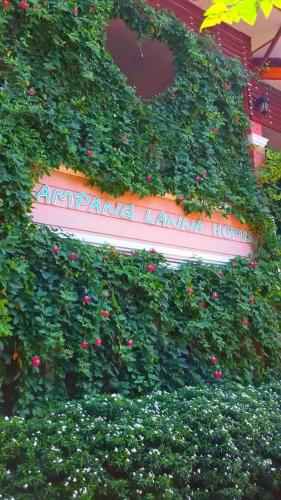 a sign obscured by a hedge with pink flowers at Lampang Lanna Home in Lampang