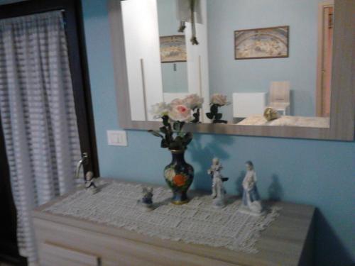 a vase with flowers in it on a dresser in a room at Dietro Piazza Maggiore in Sulmona