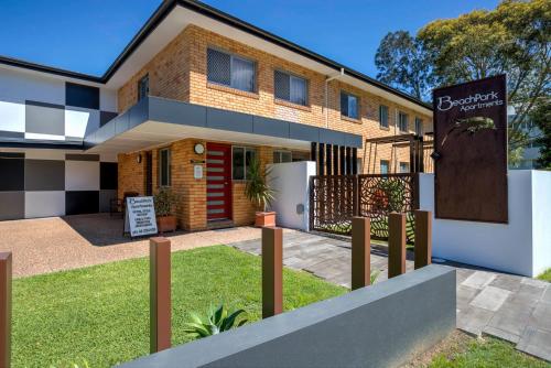 a house with a sign in front of it at Beachpark Apartments Coffs Harbour in Coffs Harbour