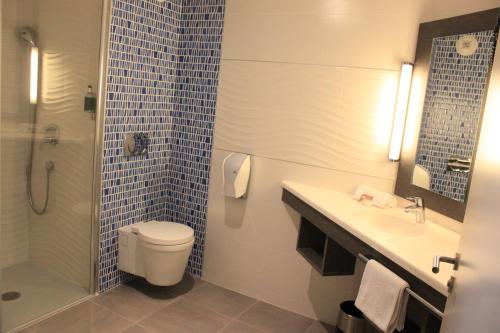 a bathroom with a toilet and a sink and a shower at The Originals Boutique, Hôtel La Chaussairie, Rennes Sud in Chartres-de-Bretagne