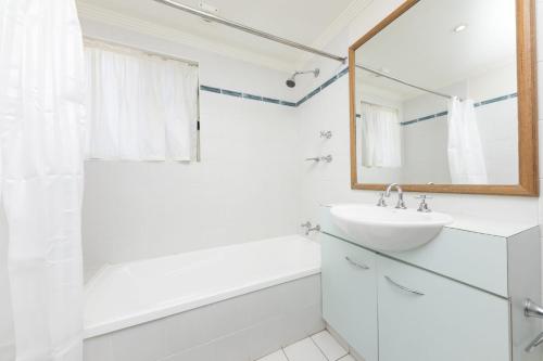 a white bathroom with a sink and a mirror at Whitesands 602 - linen not included in Forster