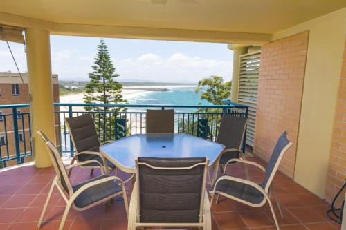 a balcony with a table and chairs and a view of the ocean at Whitesands 602 - linen not included in Forster