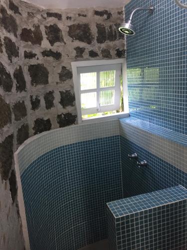 a bathroom with a blue tiled tub and a window at Suítes da Piscina in Ilhabela