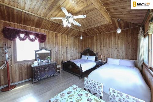 1 dormitorio con 2 camas y ventilador de techo en Billions Motel, en Gangneung