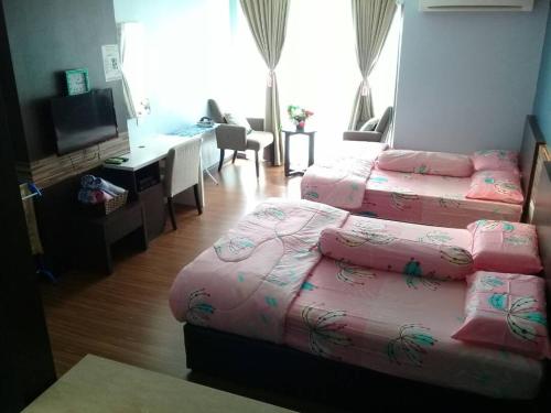 a hotel room with two beds and a desk at Best Studio Guest House in Kota Bharu