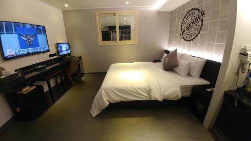 a bedroom with a bed and a desk and a television at Vovo Hotel in Seosan