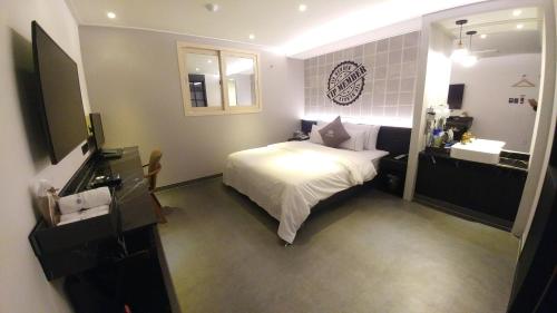 um quarto com uma cama e uma casa de banho com um lavatório em Vovo Hotel em Seosan
