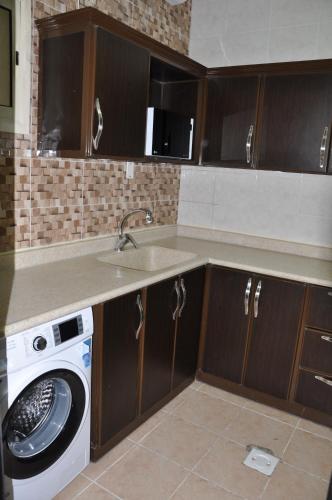 a kitchen with a sink and a washing machine at SHALLY RESIDENCE 2 in Al Khobar