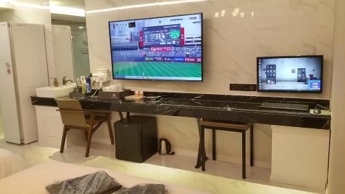 a bathroom with a desk with a television on a wall at Vovo Hotel in Seosan