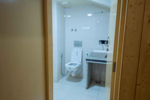a white bathroom with a toilet and a sink at Hotel Imperial Resorts in Sonāmarg