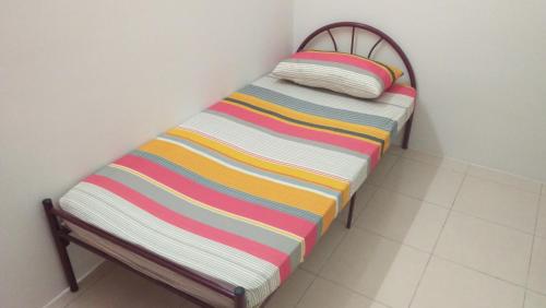 a small bed with a colorful striped blanket on it at MaiHomestay Seri Iskandar in Seri Iskandar