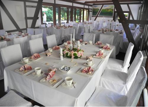 a long white table with white chairs in a room at Hotelanlage Starick in Lübbenau
